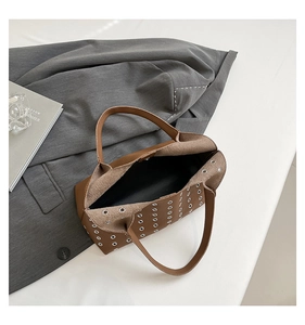 Detailed top view of brown rivet tote bag placed on a grey blazer for a stylish look