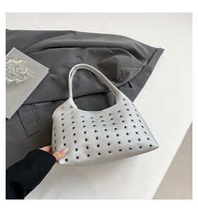 Macro shot of silver hobo bag with metallic eyelets on lychee pattern leather