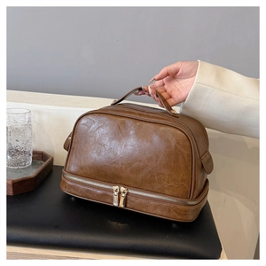 Detail of a brown double-layer PU leather makeup bag featuring a convenient side carry handle