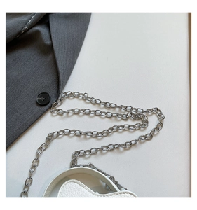 Detail of white heart-shaped mini bag with litchi texture and silver metal chain strap