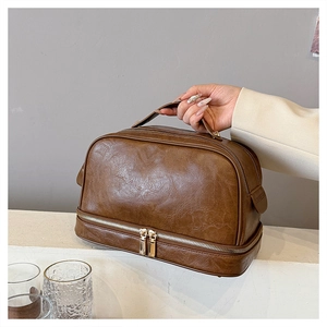 Detail of dark brown faux leather makeup bag featuring textured finish and gold zippers