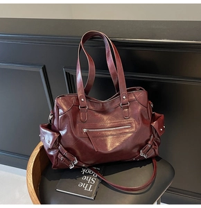 Detail of vintage dark red tote bag featuring multi-pocket design and metal rivet accents