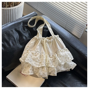 Detalle de bolso tipo saco crema con volantes florales amarillos en sofá de cuero negro