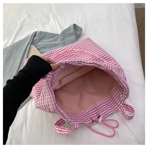 Detail showing the pink checkered canvas tote interior with a zippered pocket and lining