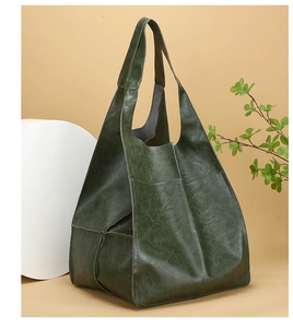 Detail view of large dark green vintage tote bag with soft leather texture and wide strap