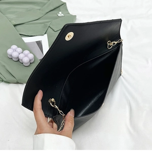 Détails de la pochette enveloppe noire avec chaîne dorée et compartiment ouvert