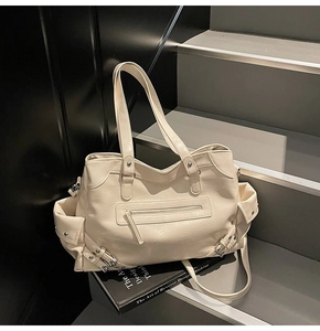 Close-up of cream tote bag featuring functional multi-pockets and metal buckle details