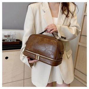 Detail view of large brown vintage textured leather makeup bag with double layer zippers