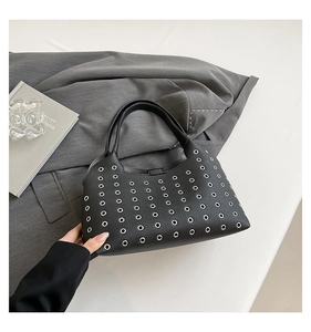 Detail of black leather handbag featuring neat silver metal eyelets and a smooth handle