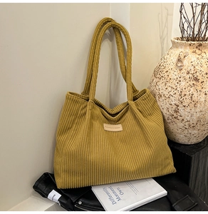 Detail of mustard yellow corduroy tote bag showing vertical rib texture and leather patch