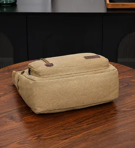 Nahaufnahme einer khakifarbenen Segeltuchtasche mit Lederakzenten auf einem Holztisch