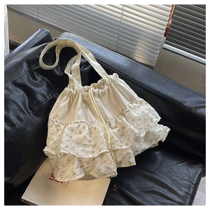 Detalle de los volantes florales y el cierre de cordón en el bolso de lona beige