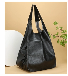 Detail view of a vintage black large capacity faux leather tote bag with front pockets