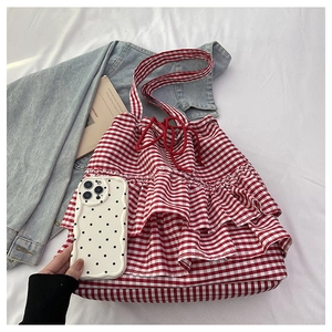 Detail of red and white checkered drawstring bag with ruffled layers on white fabric