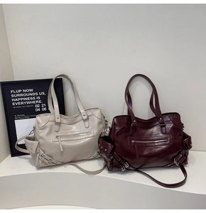 Detail of off-white and burgundy leather tote bags with rivets and shiny metal hardware