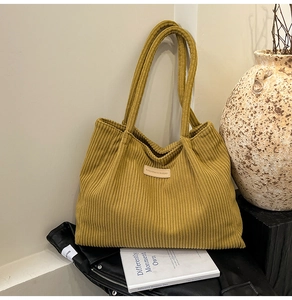Detail of mustard yellow corduroy tote bag featuring a leather patch and vintage texture
