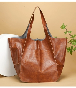 Detail of vintage brown leather tote bag showing spacious front pocket and textured finish