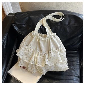Detalle de volantes florales y cierre de cordón en un bolso tote de lona color crema