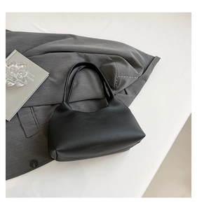Detailed macro view of black pebble grain leather texture on chic hollow rivet hobo bag
