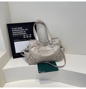 Detail of beige large tote bag with silver zippers and side buckle decor on white steps