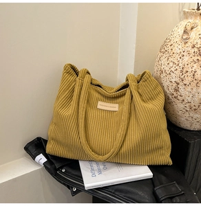 Detail view of mustard yellow corduroy tote bag with leather logo patch and soft texture