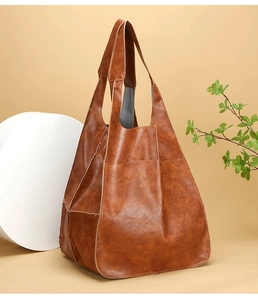 Detailed close-up showing the brown vintage leather texture and side pocket of the tote bag
