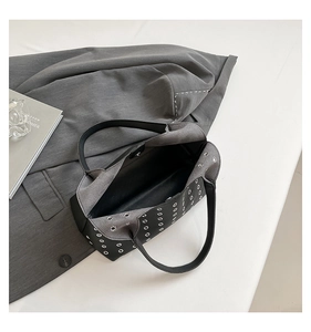 Detailed top view of a rivet cutout underarm bag with silver eyelets and patchwork design