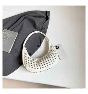 Detail der weißen Hobo-Tasche aus Leder mit silbernen Nieten und modischen Lifestyle-Accessoires
