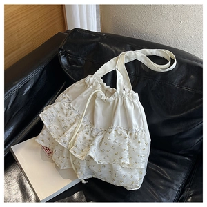 Detalle del bolso tote blanco con cordón y volantes florales amarillos en sofá negro