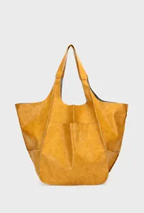 Detail view of the yellow leather tote bag showing textured surface and large outer pocket