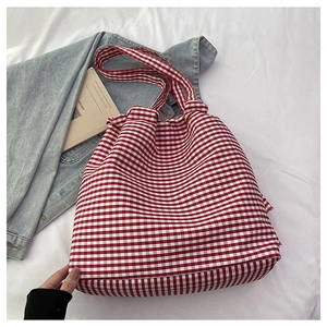 Detail of red and white checkered canvas tote bag with matching soft handles and props