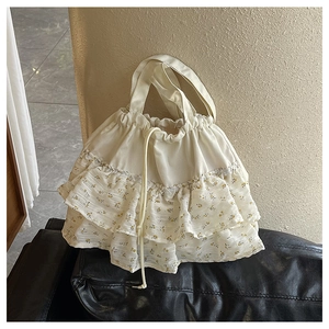Detalle de bolso blanco con cordón y capas de volantes con estampado de flores amarillas