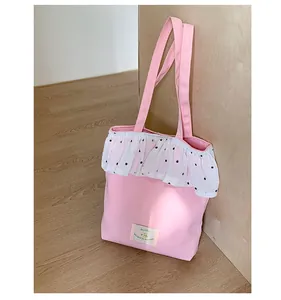 Detail der rosa Canvas-Tragetasche mit weißem Rüschen-Tüllbesatz und gewebtem Etikett