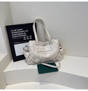 Detailed view of cream white tote bag featuring silver buckles and functional side pockets