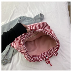 Detail of red gingham canvas tote bag featuring pink lining and interior zipper pocket