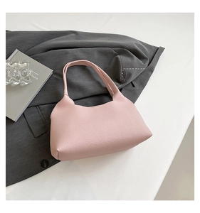 Pink pebbled leather shoulder bag shown on a stylish magazine and gray blazer background