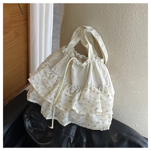 Detalle de bolso tote floral crema con volantes de tres capas y un cierre de cordón ajustable