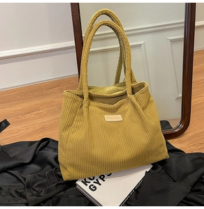 Detail of ginger yellow corduroy tote bag featuring vertical ribbed texture and logo patch