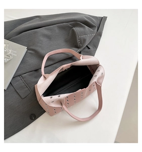 Detail view of pink leather handbag showing silver metal eyelets and magnetic closure