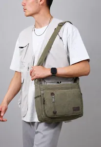 Modell mit armee-grüner Canvas-Umhängetasche mit Reißverschlusstaschen und breitem Gurt