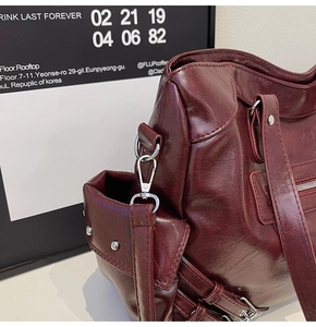 Detailed side view of dark wine red tote bag showing silver rivets and side pocket