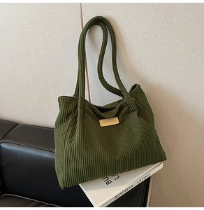 Detail of green corduroy tote bag with fashion leather patch and striped texture