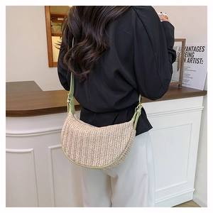 Dettaglio borsa a mezzaluna in paglia intrecciata con finiture in pelle verde chiaro