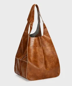 Close-up of vintage brown leather tote bag showing rich lychee grain texture and stitching