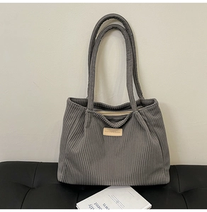Macro shot of grey corduroy tote bag texture with fashion label on black bench