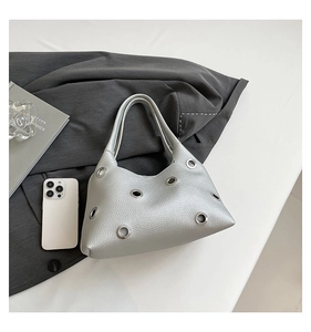 Detailed macro view of silver rivet textured handbag with smartphone for size scale