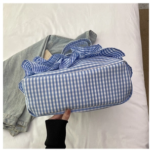 Detail of blue and white checkered canvas tote bag with ruffled edges and large capacity