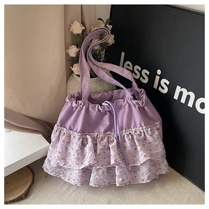 Detalle de bolso bandolera morado con flores, cierre de cordón y textura de lona suave