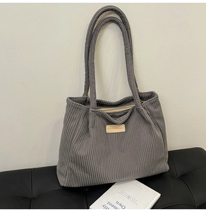 Close-up of grey corduroy tote bag featuring vertical texture and a fashion label detail