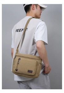 Macro detail of khaki canvas shoulder bag showing reinforced stitching and leather pullers